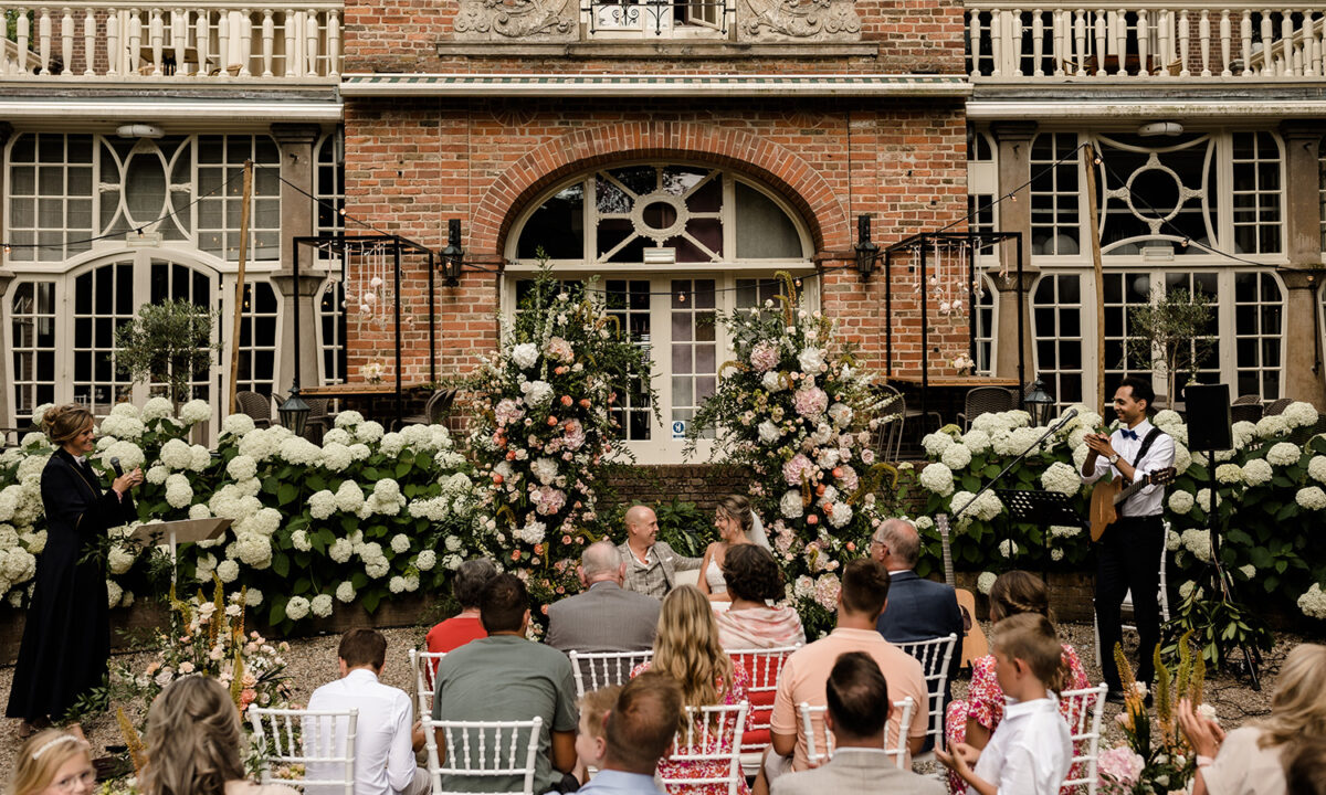 Aanzicht ceremonie met livemuziek door Khalil en ambtenaar Reinolda als ambtenaar in de tuin van Kasteel Kerckebosch