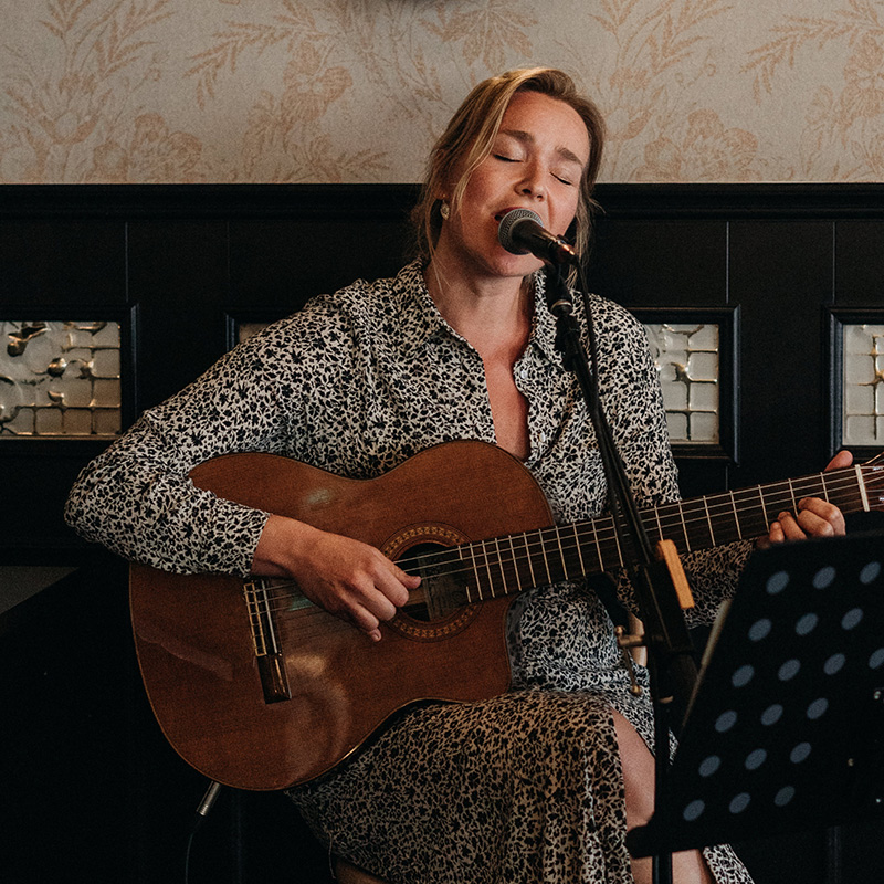 Dana zingt en speelt gitaar tijdens een huwelijksceremonie.